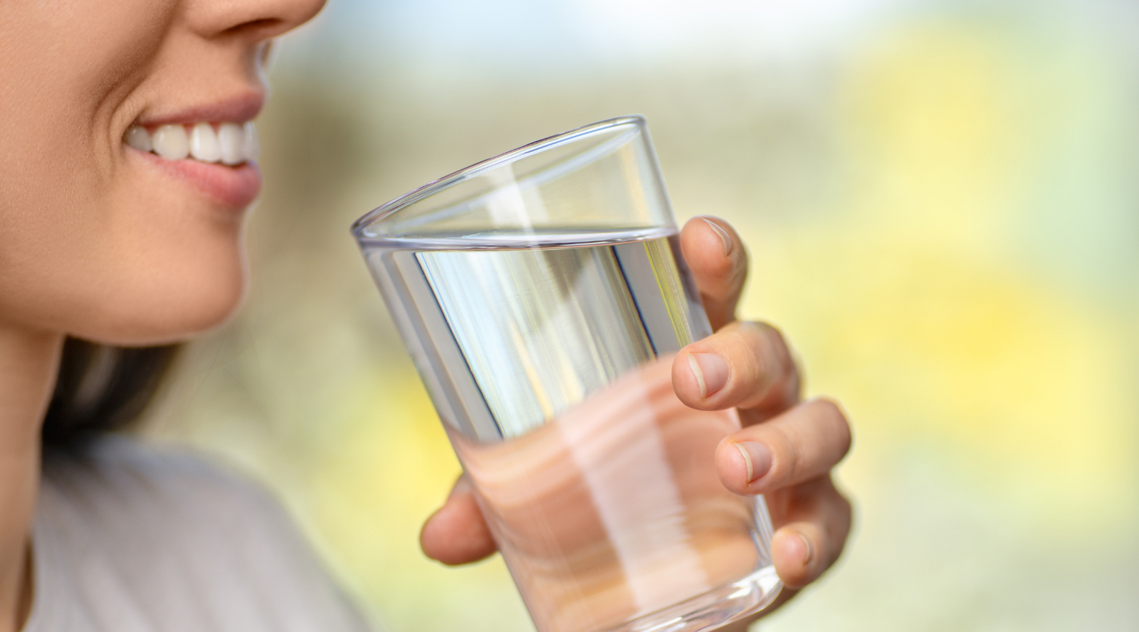 Person holding a glass of water with a blurred background