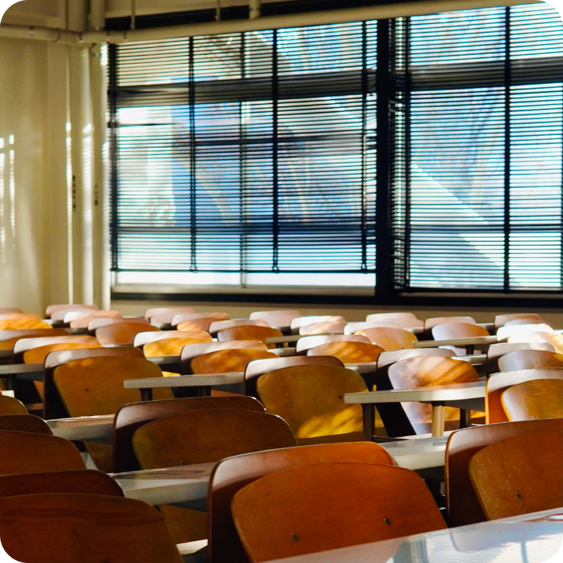 Empty classroom with rows of desks and windows with blinds