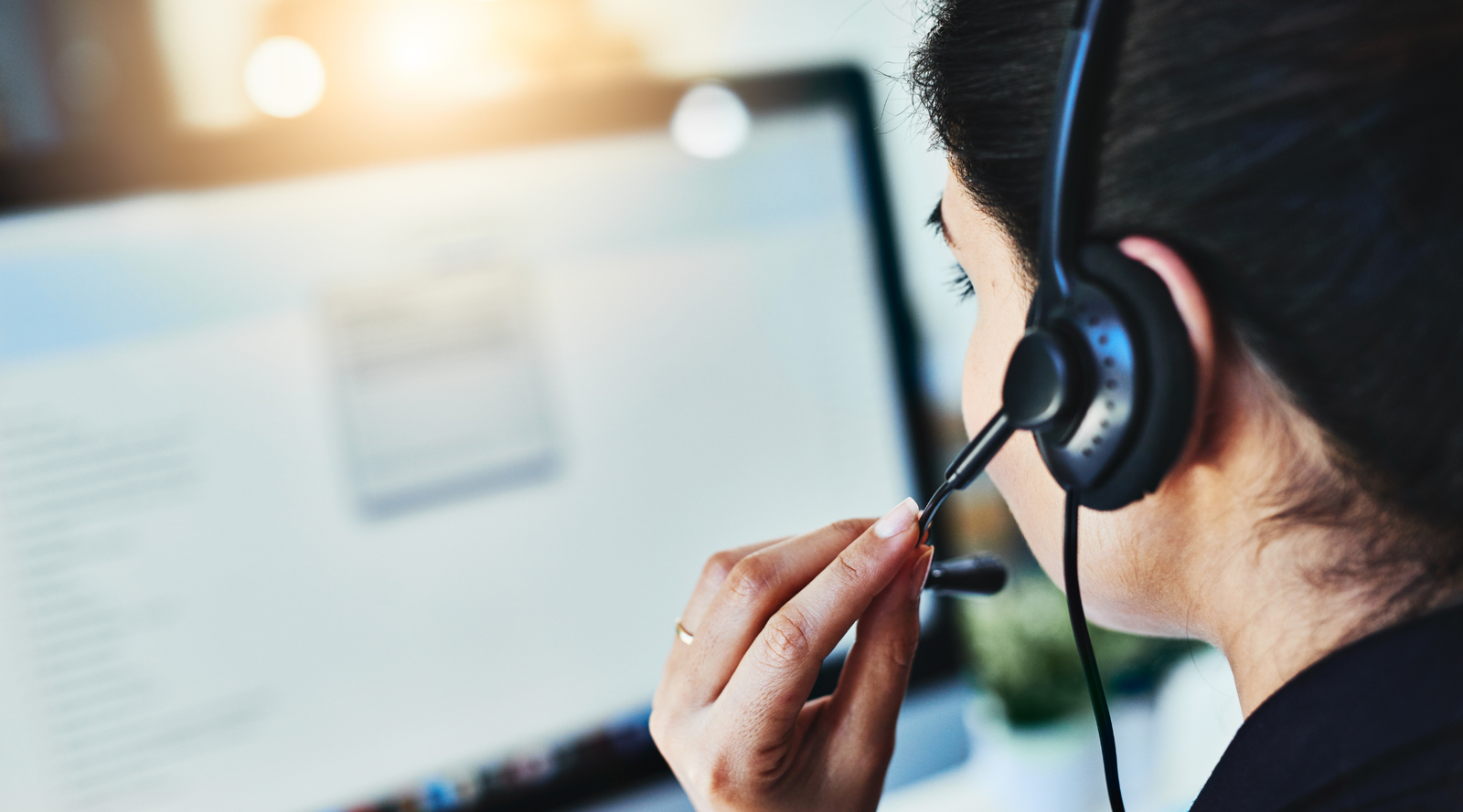 Person wearing a headset in front of a computer screen